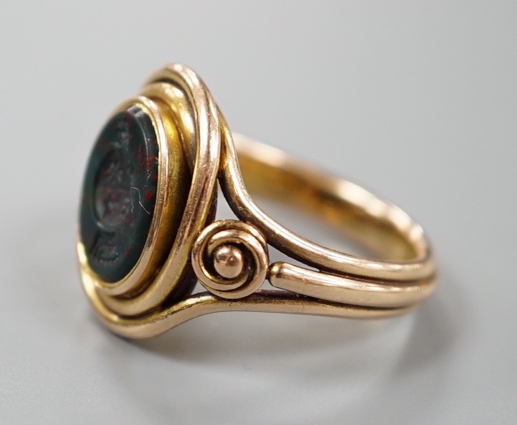 A Victorian yellow metal and oval bloodstone set signet ring, the matrix carved with family crest, size O, gross weight 8.6 grams.